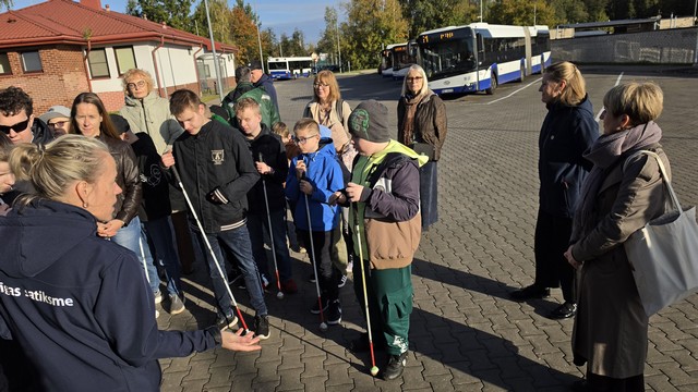 Skolēni ar skolotājām stāv autobusu galapunktā Jugla 3.