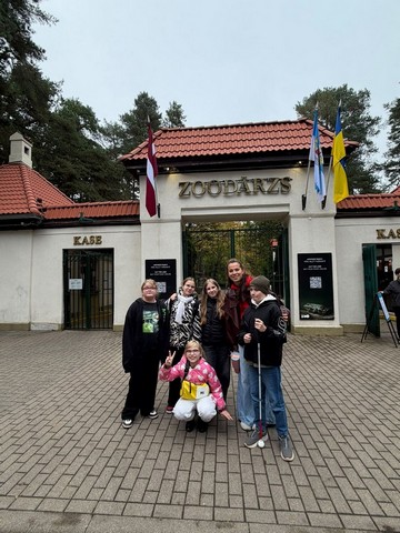 Skolēni un skolotāja pie ieejas Zooloģiskajā dārzā.
